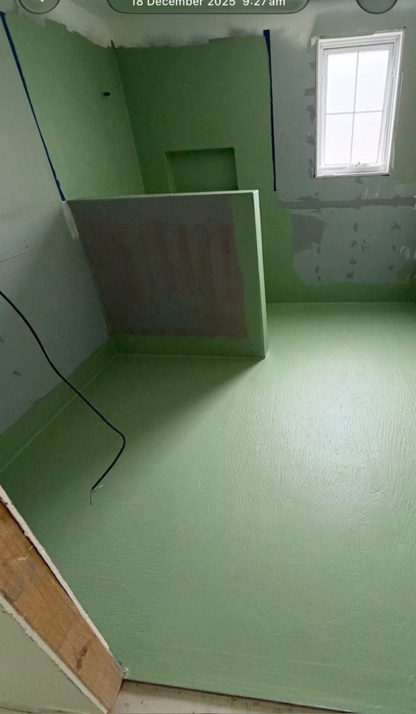 Bathroom floor and walls coated in green waterproofing membrane